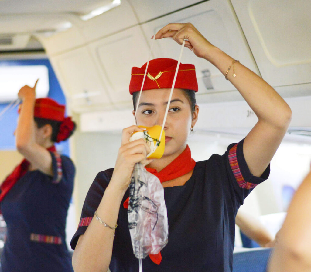 Air stewardess showing how to wear an Oxygen Mask, Photo by Alejandro Quiñonez